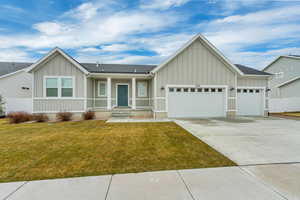 Ranch-style house featuring fence, an attached garage, board and batten siding, driveway, and a front yard
