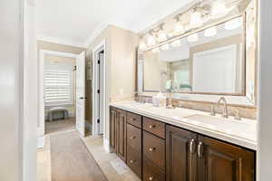 Bathroom featuring double vanity, ornamental molding, a sink, and a tile shower