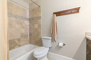 Full bathroom with baseboards, toilet, vanity, and bathing tub / shower combination