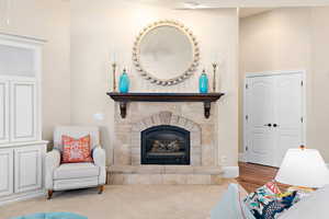 Living room with carpet flooring and a stone fireplace