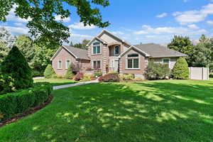 View of front of home with brick siding, fence, and a front lawn