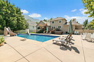 View of pool featuring a hot tub, a patio, a fenced backyard, a water slide, and a deck with mountain view