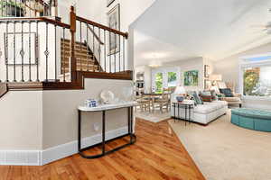 Living room featuring visible vents, stairs, ceiling fan, wood finished floors, and lofted ceiling
