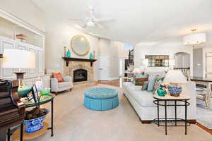 Living area with arched walkways, a fireplace, high vaulted ceiling, and a ceiling fan