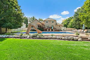 View of swimming pool with a fenced backyard, a deck, a water slide, and a yard