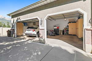 Garage featuring concrete driveway, a mountain view, and fence