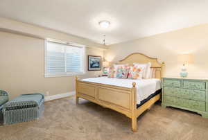 Bedroom with baseboards, light colored carpet, and a textured ceiling