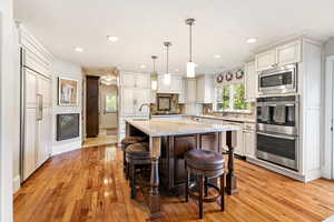 Kitchen with decorative backsplash, light wood-style flooring, a breakfast bar, and built in appliances