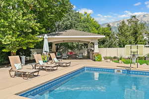 View of pool featuring fence, a patio, a fenced in pool, a gazebo, and a mountain view