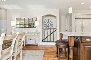 Dining area featuring recessed lighting, arched walkways, and light wood-type flooring