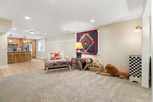 Living area with light carpet, baseboards, light wood finished floors, and recessed lighting