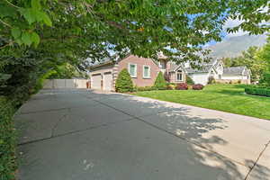 View of front of house with fence, driveway, a mountain view, a front lawn, and brick siding