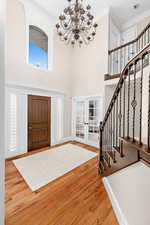 Foyer entrance featuring french doors, a high ceiling, a chandelier, and wood finished floors