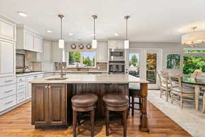 Kitchen featuring a kitchen island with sink, light wood finished floors, a sink, and stainless steel appliances