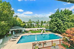 View of pool featuring a patio area, a trampoline, a water slide, fence, and a mountain view