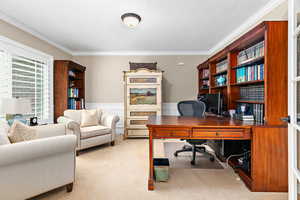 Carpeted home office with wainscoting and crown molding