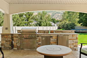 View of patio featuring fence, a grill, exterior kitchen, a trampoline, and a sink