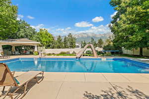 View of swimming pool with a mountain view, a fenced in pool, a gazebo, and a water slide