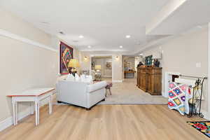 Living area with a textured ceiling, light wood-style flooring, baseboards, visible vents, and recessed lighting