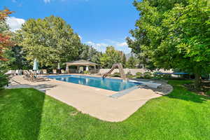 Pool with a water slide, a patio, a gazebo, a lawn, and a diving board