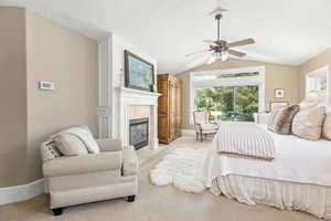 Bedroom with a tile fireplace, baseboards, lofted ceiling, and light colored carpet