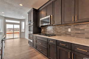 Kitchen featuring light countertops, stainless steel appliances, a textured ceiling, decorative backsplash, and light wood-style flooring