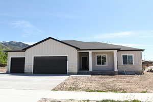 View of front of property with a garage, driveway, board and batten siding, and roof with shingles