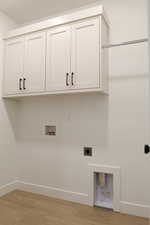 Laundry room with electric dryer hookup, cabinet space, hookup for a washing machine, and baseboards