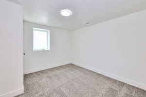 Unfurnished room featuring carpet floors, a textured ceiling, baseboards, and visible vents