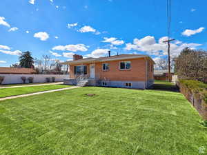 View of front of property featuring a fenced backyard, brick siding, a chimney, and a front lawn