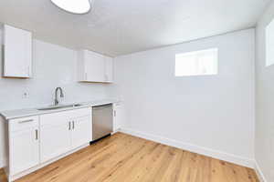 Kitchen with light countertops, tasteful backsplash, a sink, light wood-style floors, and stainless steel dishwasher