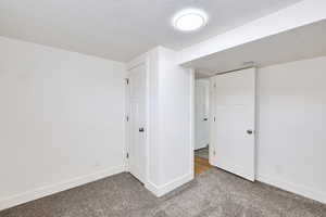 Unfurnished bedroom with carpet floors, baseboards, and a textured ceiling