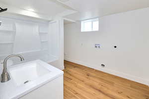 Washroom featuring hookup for a washing machine, light wood finished floors, laundry area, a sink, and hookup for an electric dryer