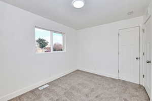 Carpeted spare room with a textured ceiling, baseboards, and visible vents
