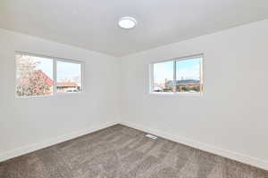 Empty room featuring baseboards, visible vents, and carpet floors