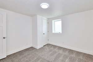 Carpeted spare room featuring baseboards and a textured ceiling