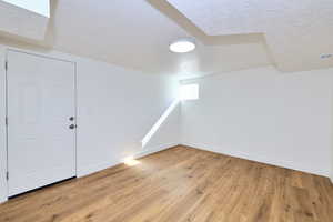 Spare room featuring a textured ceiling, baseboards, light wood finished floors, and visible vents