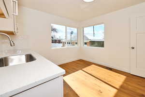 Kitchen featuring visible vents, white cabinetry, a sink, and light wood-type flooring