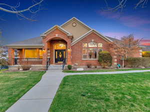 Traditional-style home featuring brick siding, a front lawn, and covered porch