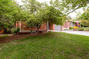 View of front of house with driveway, brick siding, a front yard, and an attached garage