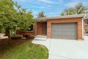 Single story home with driveway, brick siding, and a garage