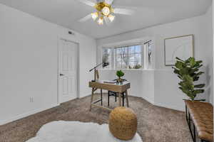 Office area with baseboards, visible vents, carpet, and a ceiling fan