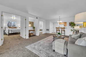 Carpeted living area with an inviting chandelier and visible vents