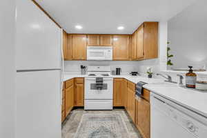 Kitchen with light countertops, a sink, recessed lighting, and white appliances