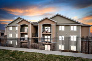 View of front of property featuring a balcony, stucco siding, and a fenced front yard