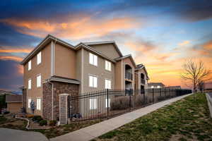 Property exterior at dusk featuring stone siding, fence private yard, and stucco siding