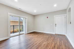 Empty room featuring wood finished floors, arched walkways, baseboards, and recessed lighting
