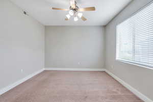 Unfurnished room featuring light carpet, a ceiling fan, and baseboards