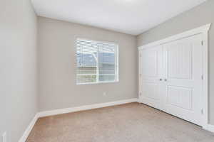 Unfurnished bedroom with carpet floors, baseboards, and a closet