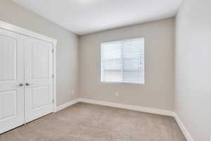 Unfurnished bedroom featuring carpet flooring, baseboards, and a closet